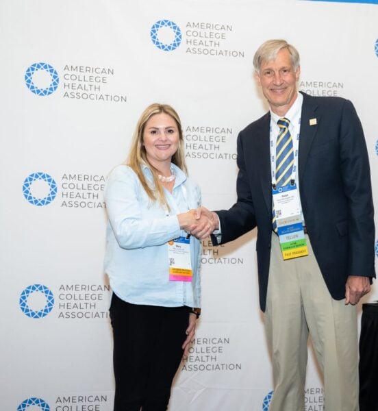 Two professional people posing with an award certificate