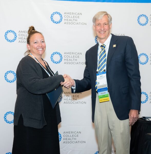 Two professional people posing with an award certificate