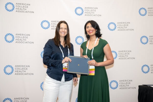 Two professional people posing with an award certificate