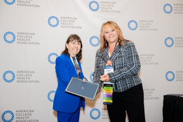 Two professional people posing with an award certificate