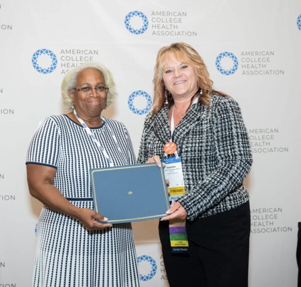 Two professional people posing with an award certificate