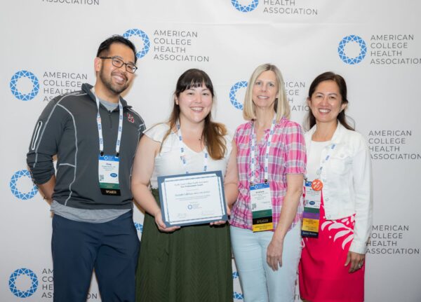 Group of people posing with an award winner holding a certificate