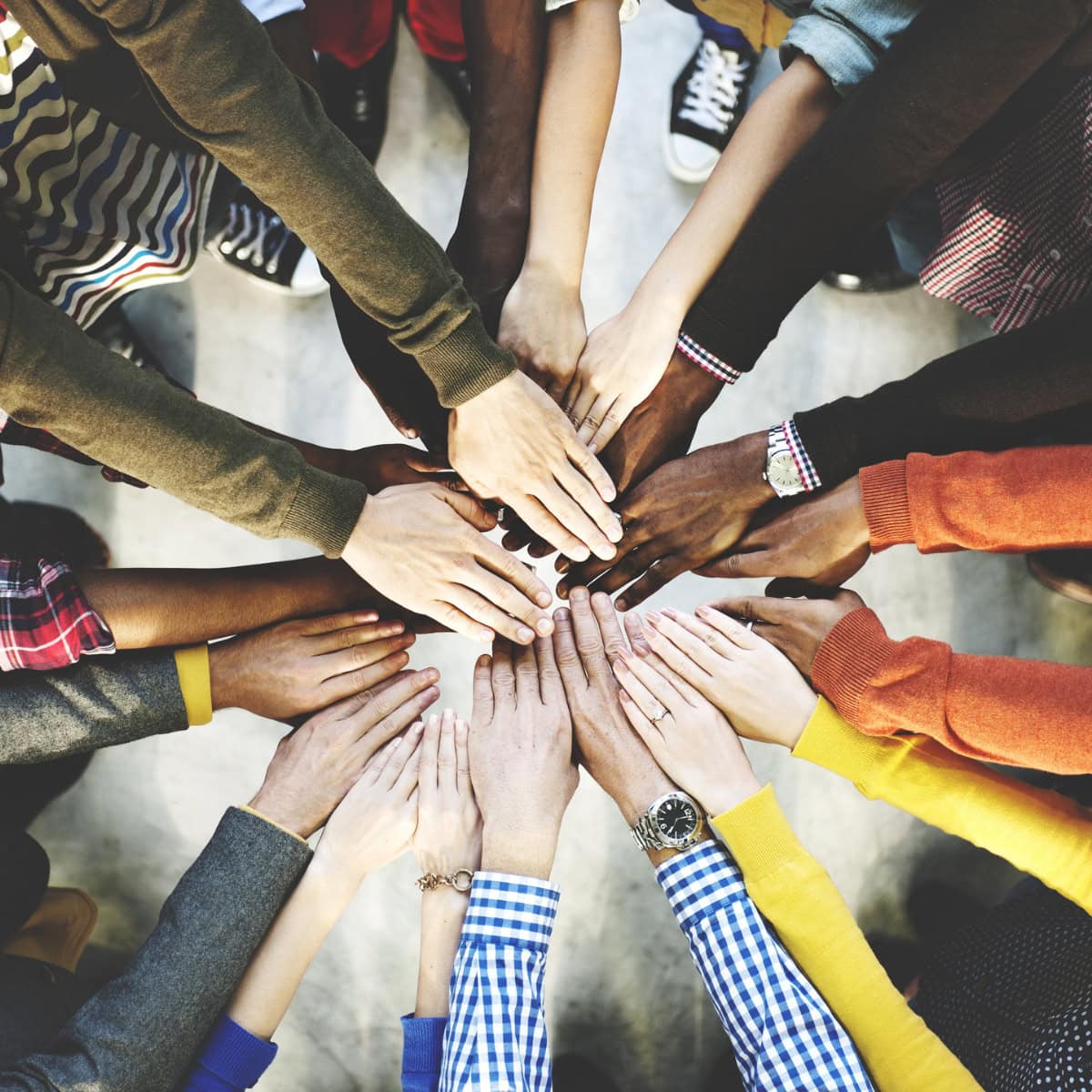 A close-up of people putting their hands together in circle, indicating teamwork