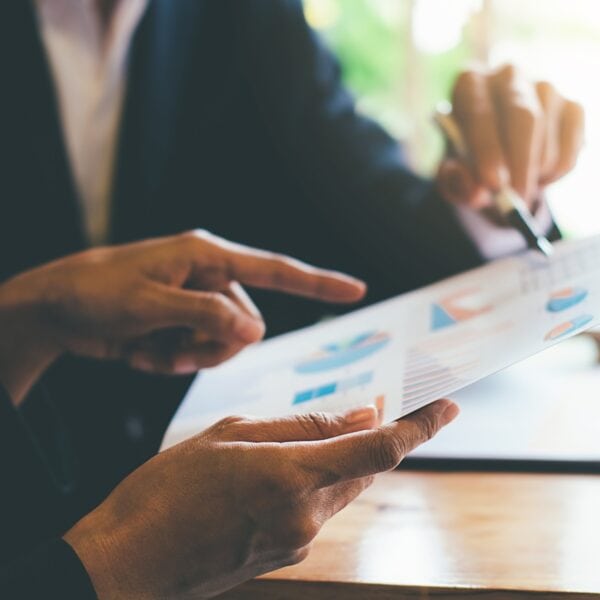 A close up of two people holding a report and reviewing it