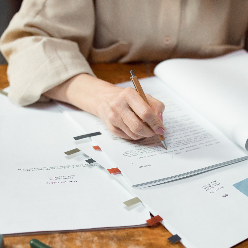 A person reading and revising a report while sitting at a desk.