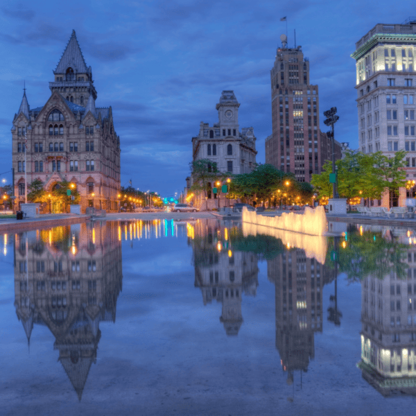 Buildings in Syracuse reflected in the water at dusk
