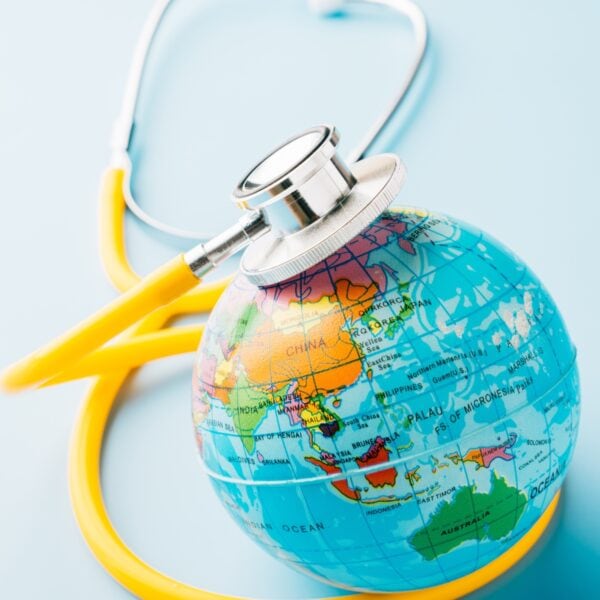A yellow stethoscope on top of a small globe figurine