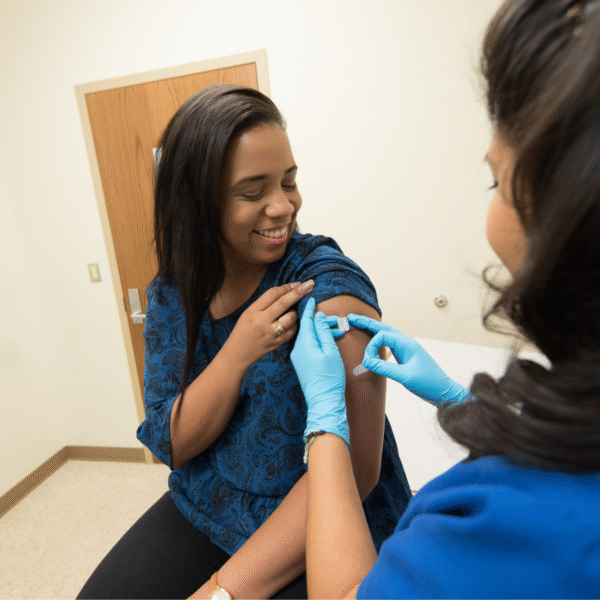 Clinician putting a bandage on a patient's arm after vaccination