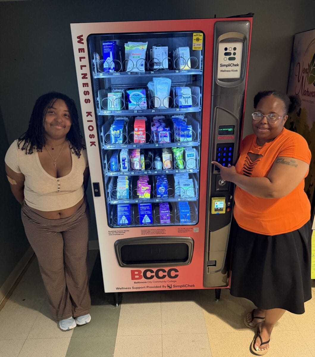 Two college students standing next to a wellness vending machine