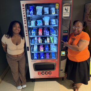 Two college students standing next to a wellness vending machine