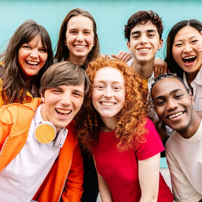 A group of students posing together and smiling in front of a blue background