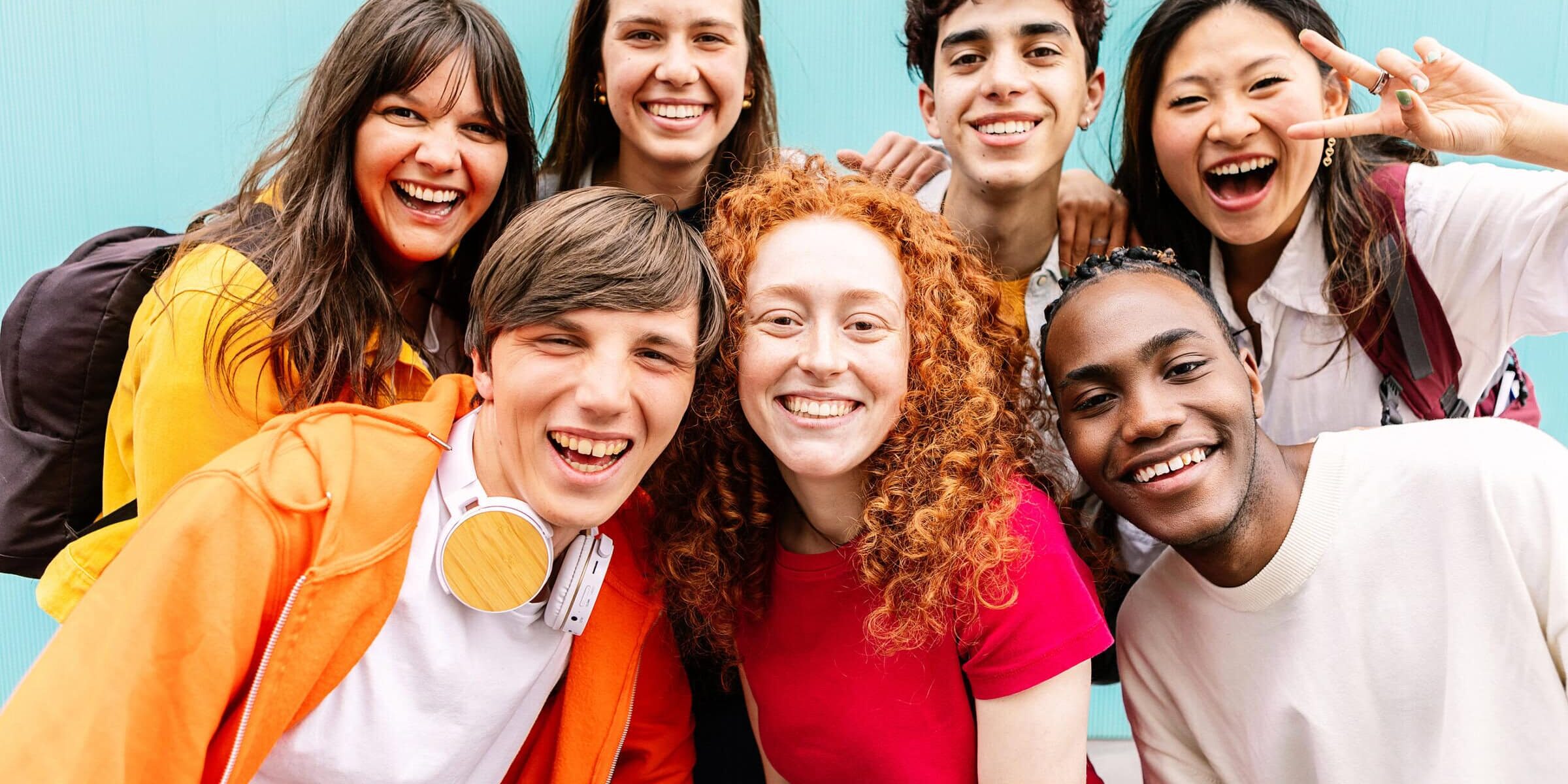 A group of students posing together and smiling in front of a blue background