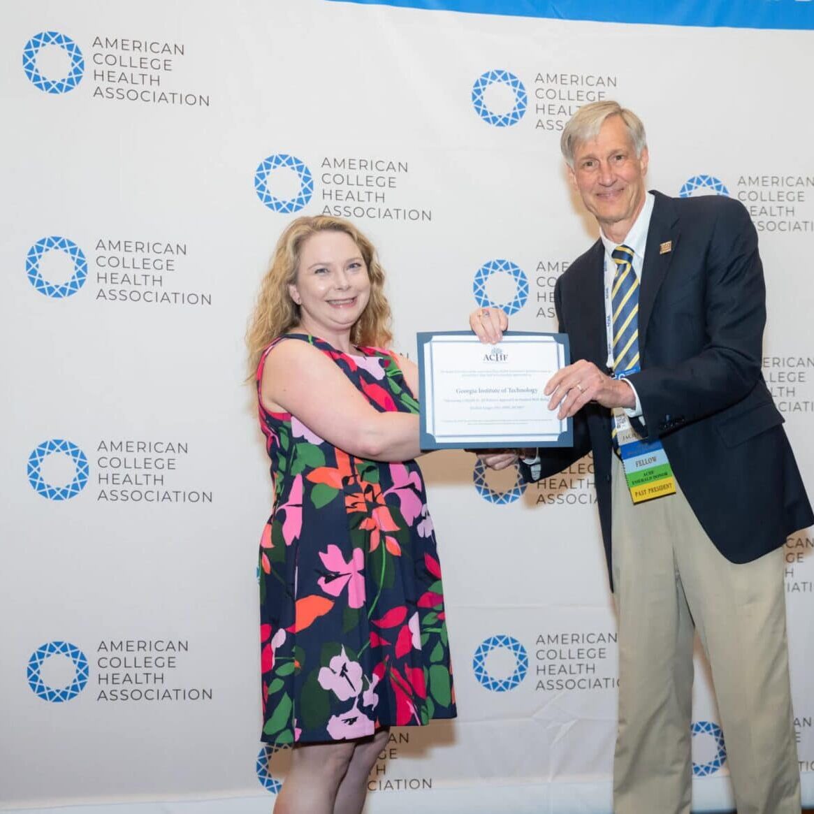 Two professional people posing with an award certificate