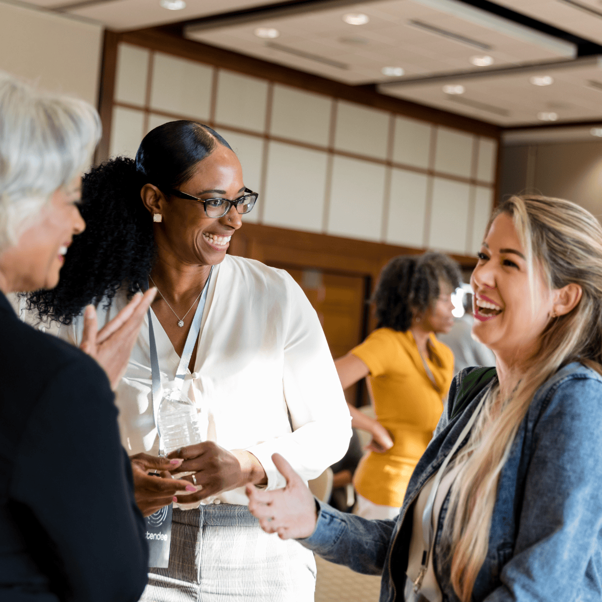 A group of professionals smiling and talking to each other at a meeting