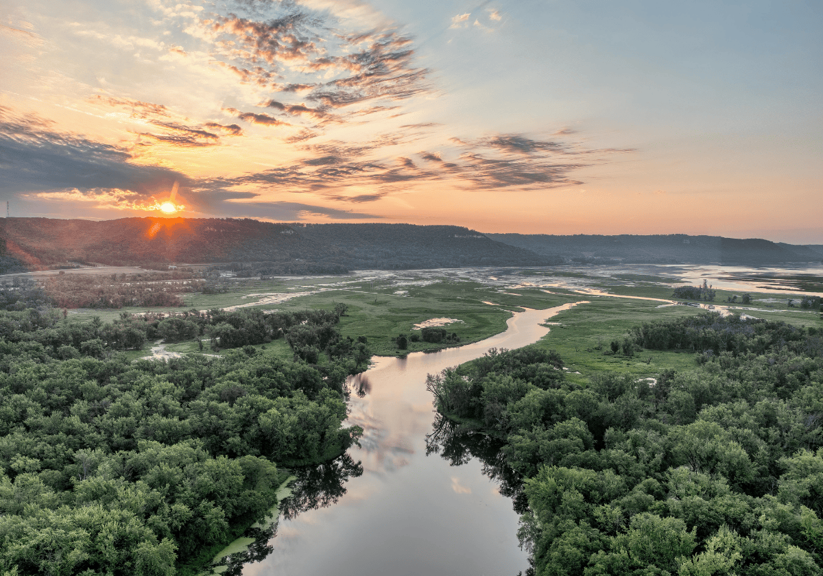 Scenic Sunrise Over Mississippi River in Minnesota - aerial view of a winding river between many trees, with a sunrise in the background