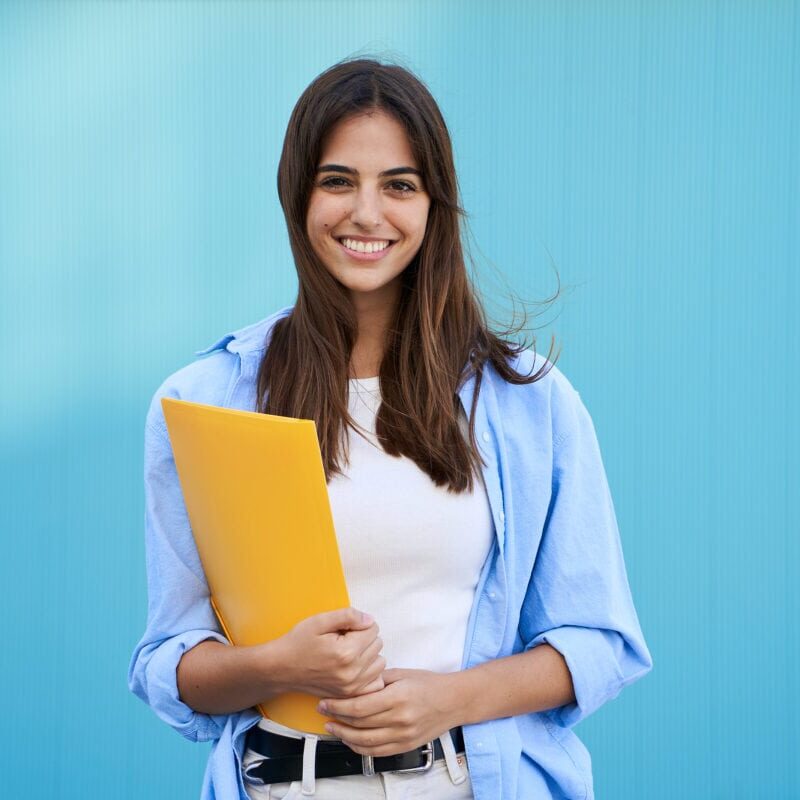 A smiling female college student holding a yellow folder