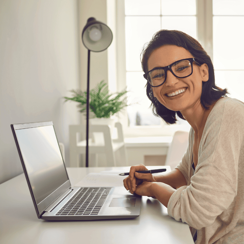 A woman working on her laptop at a desk and smiling