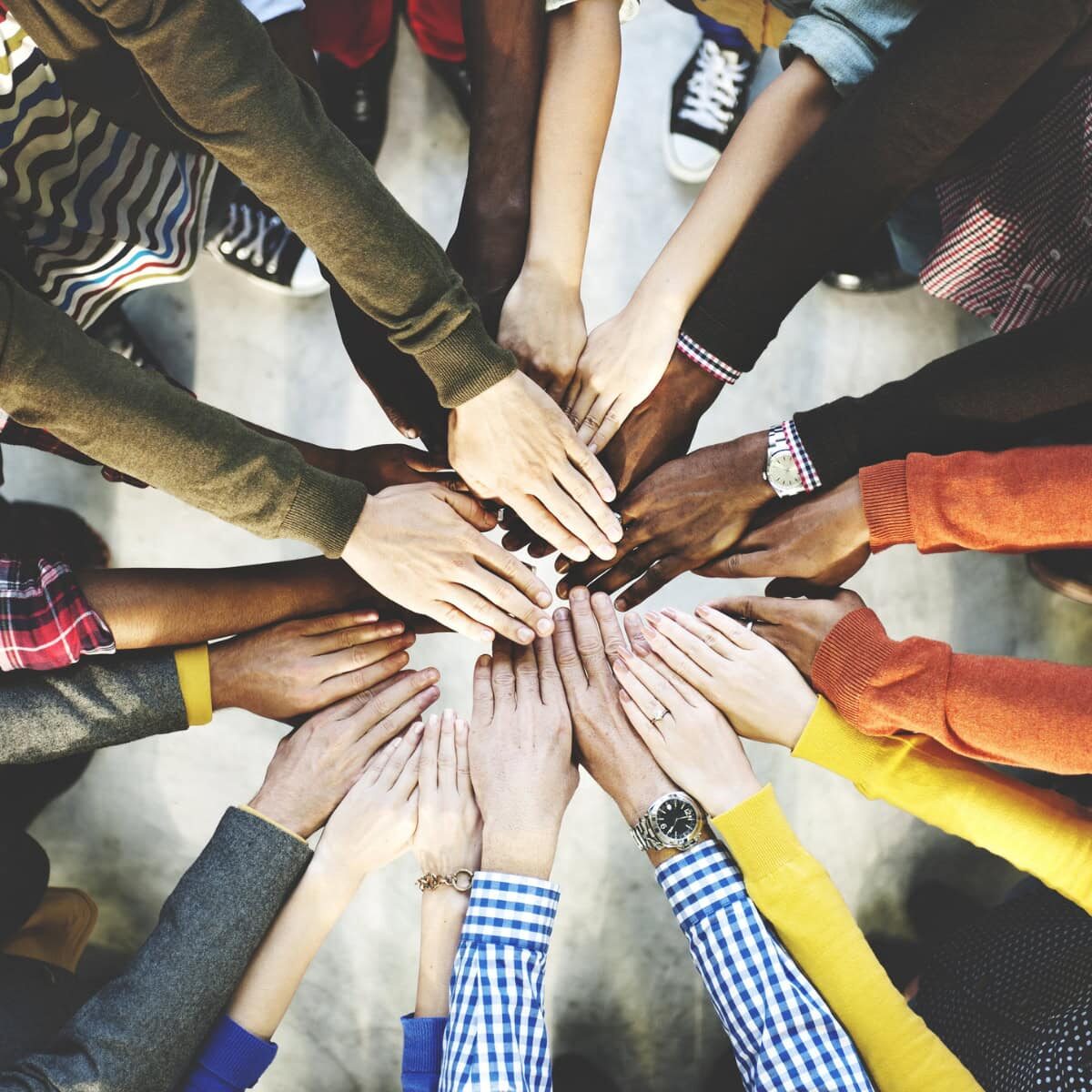 A close-up of people putting their hands together in circle, indicating teamwork