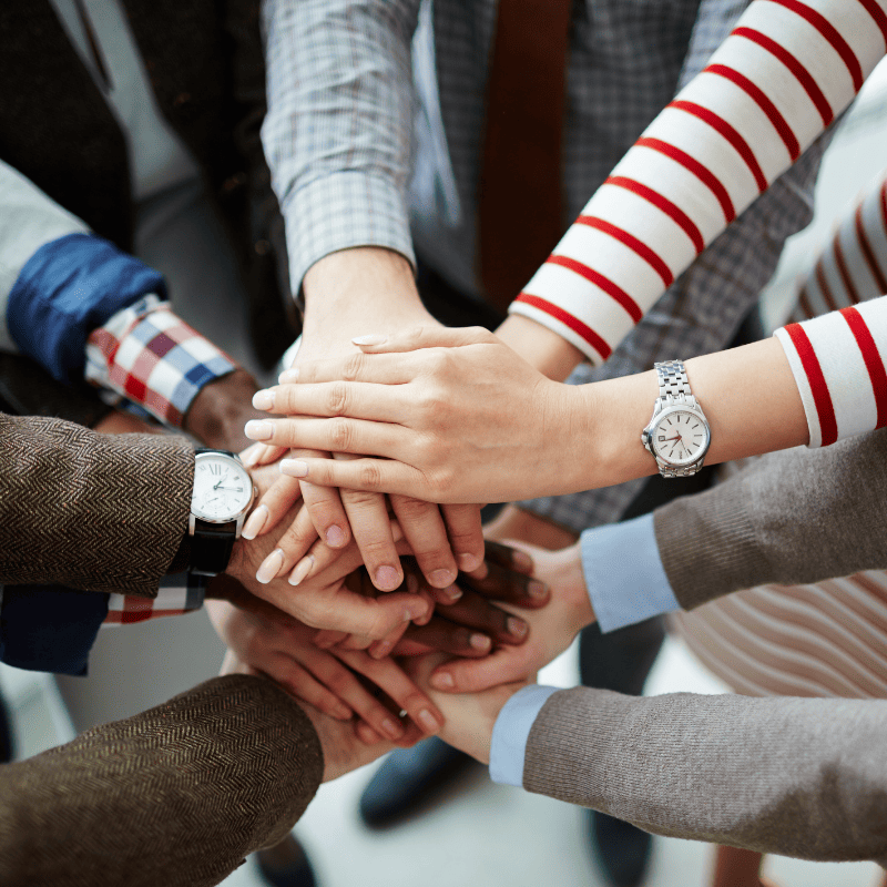 A group of professionals putting their hands in together in a circle, representing partnership