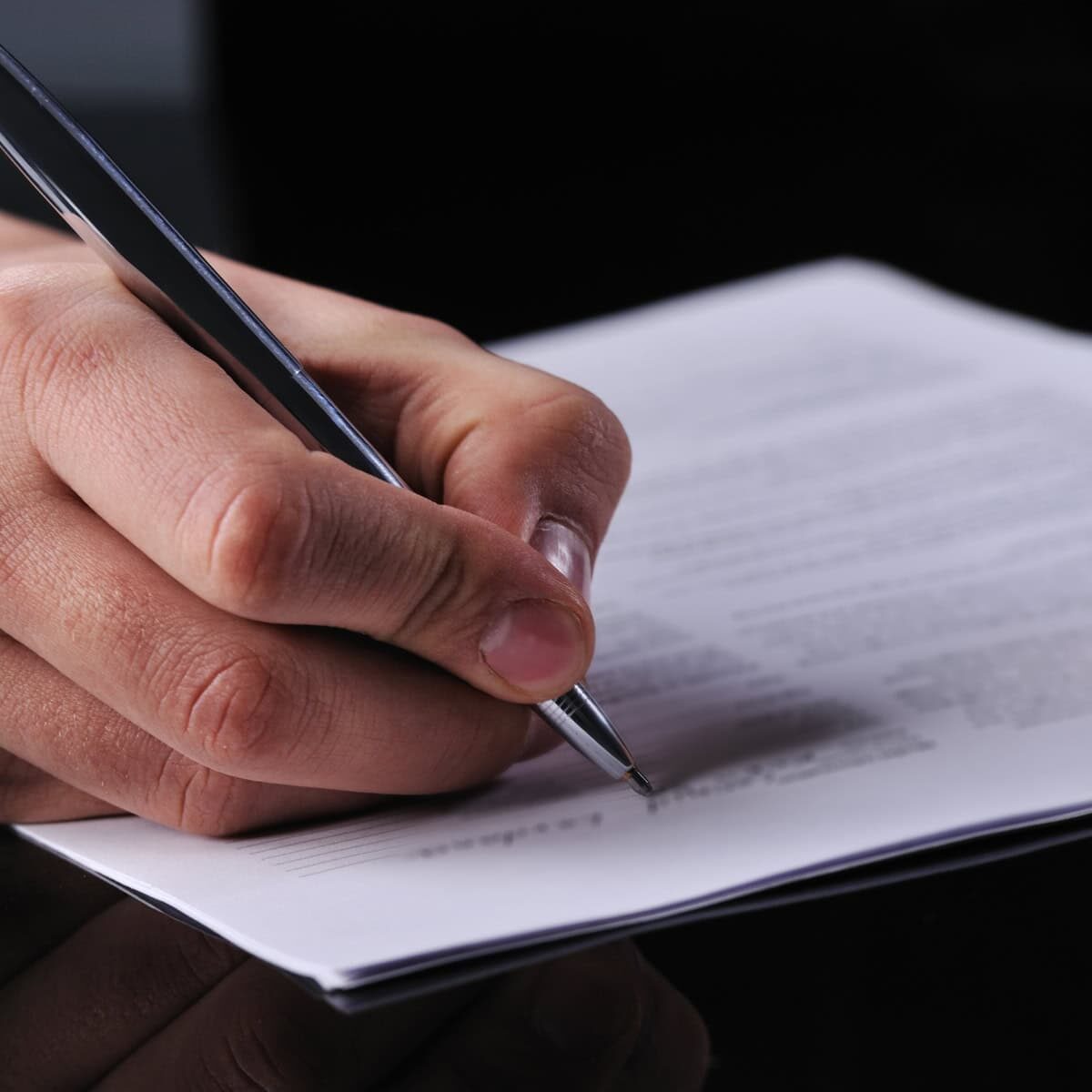 An close-up of a hand writing on a document with a pen