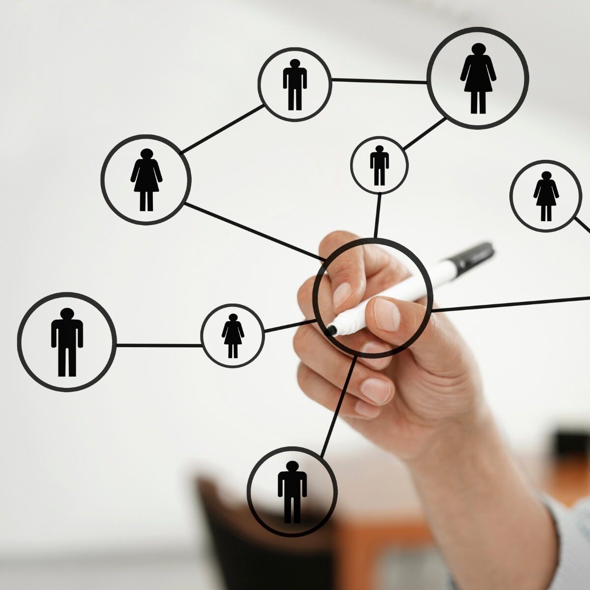 A hand drawing male and female people icons in circles with a black marker