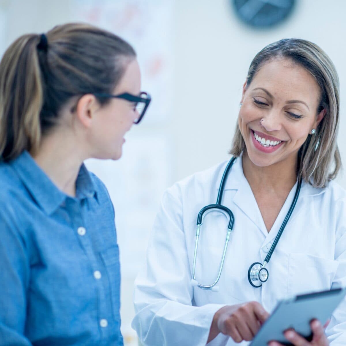 Smiling female doctor conversing with a young woman patient
