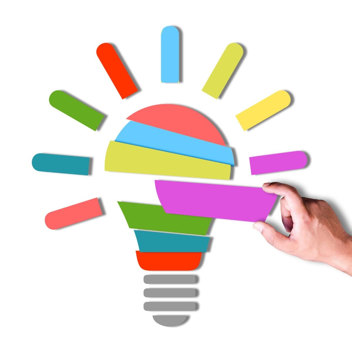 A person assembling an image of a lightbulb with strips of different color paper