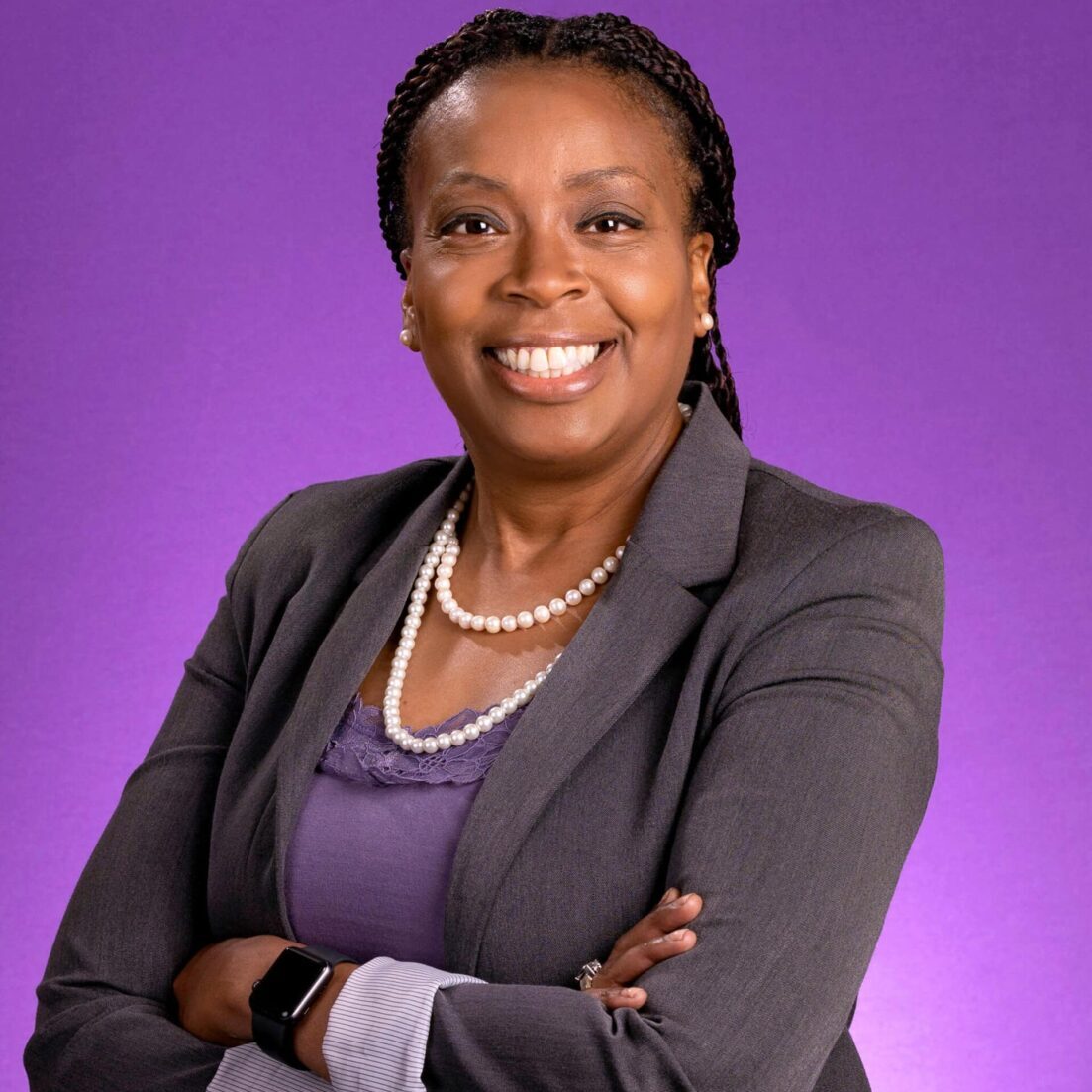 Empowered professional woman in business attire, smiling confidently with arms crossed.