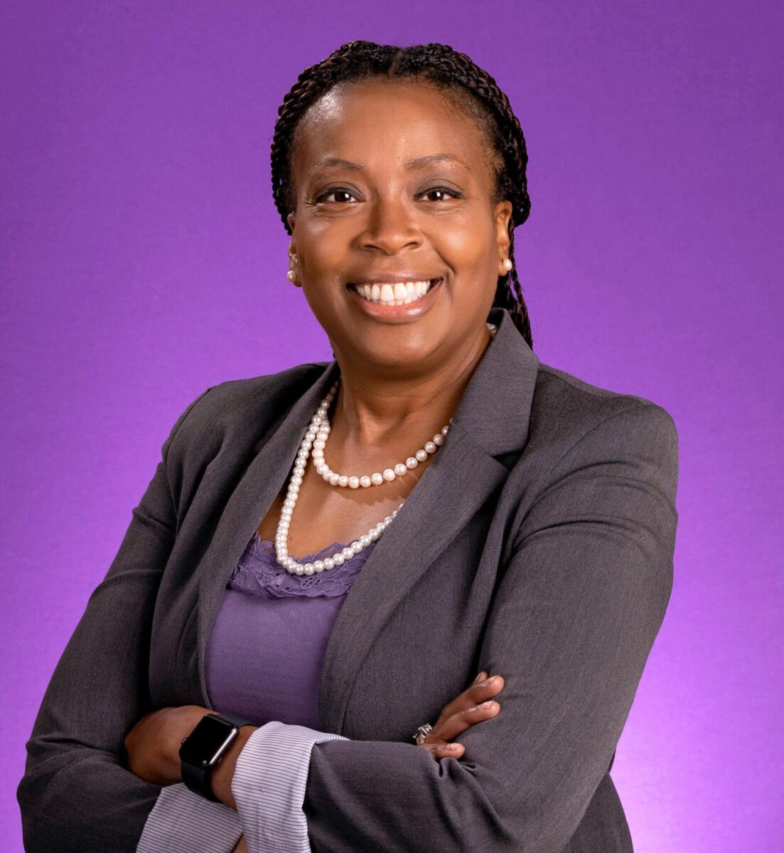 Empowered professional woman in business attire, smiling confidently with arms crossed.